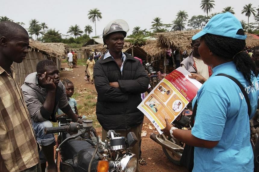 A UNICEF worker speaks with drivers of motorcycle taxis about the symptoms of Ebola virus disease (EVD) and the best practices to help prevent its spread, in the city of Voinjama, in Lofa County, Liberia in this April 2014 UNICEF handout photo. The P