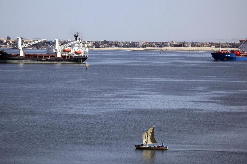 A fisherman travels on a boat near container ships in the Suez Canal, near Ismailia port city, northeast of Cairo on May 2, 2014.&nbsp;Egypt plans to build a new Suez Canal alongside the existing 145-year-old historic waterway in a multi-billion doll