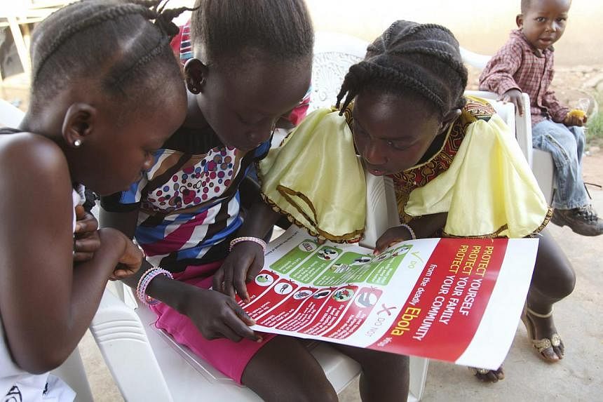 Girls look at a poster, distributed by UNICEF, bearing information on and illustrations of best practices that help prevent the spread of Ebola virus disease (EVD), in the city of Voinjama, in Lofa County, Liberia in this April 2014 UNICEF handout ph