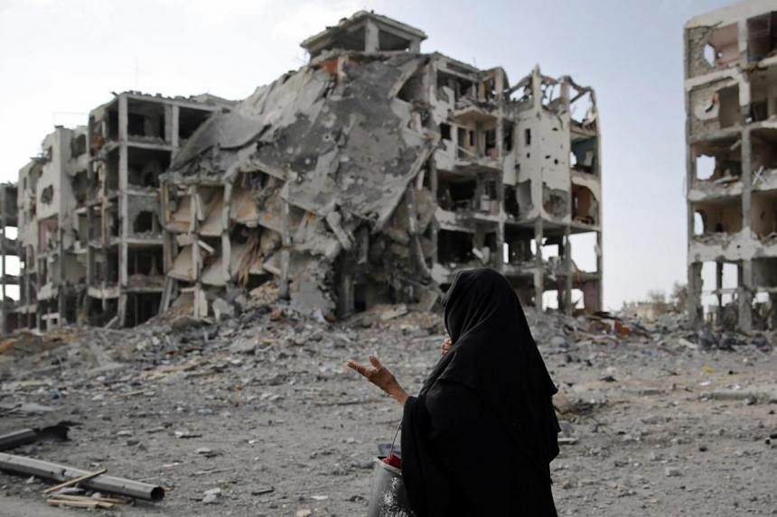 A Palestinian woman walks past buildings destroyed by what police said were Israeli airstrikes and shelling in the town of Beit Lahiya in the northern Gaza Strip August 3, 201. Hopes were raised Tuesday for an end to four weeks of fierce fighting aft