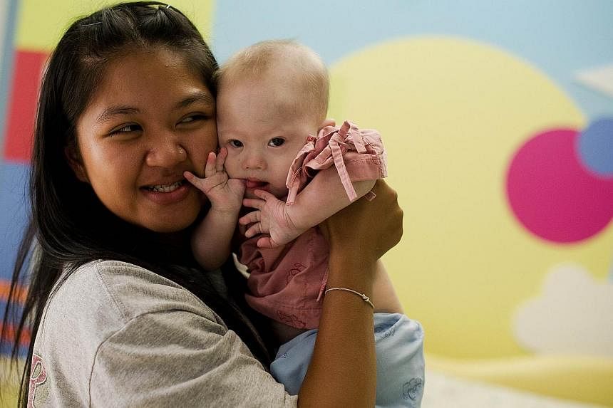 The Australian father in the furore surrounding Baby Gammy, seen here with Thai surrogate mother Pattaramon Chanbua, has allegedly been convicted of child indecency, Australian media reported. -- PHOTO: AFP