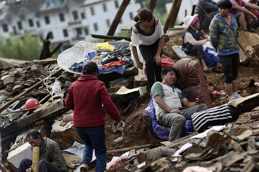 A man sits on a sofa next to his collapsed house as rescuers try to find his wife and child who were buried underneath the debris after an earthquake hit Longtoushan township of Ludian county, Yunnan province on Aug 4, 2014. -- PHOTO: REUTERS
