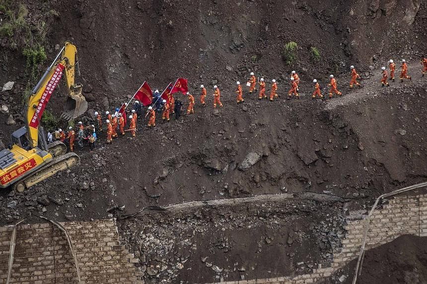 A group of rescue workers walk through a collapsed road at an earthquake hit area in Ludian county, Zhaotong, Yunnan province on Aug 5, 2014. -- PHOTO: REUTERS