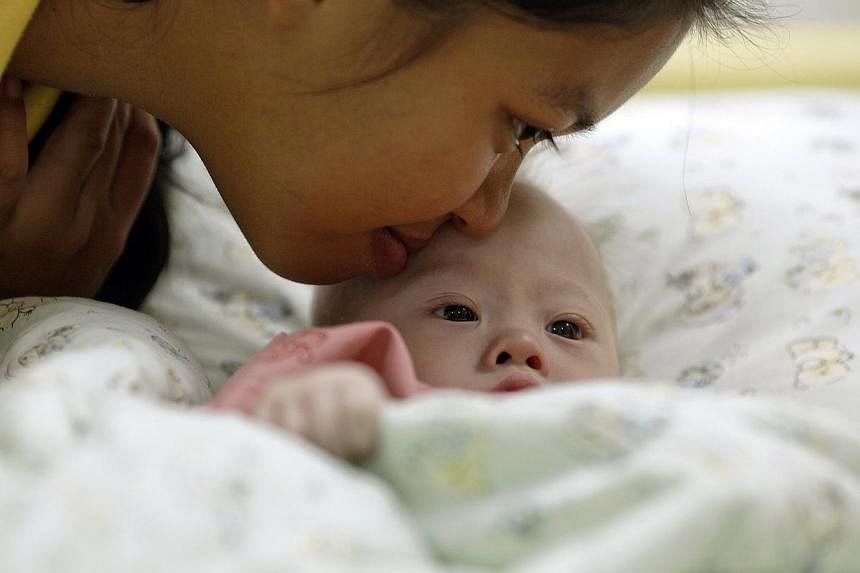 Gammy, a baby born with Down's Syndrome, is kissed by his surrogate mother Pattaramon Janbua at a hospital in Chonburi province on Aug 3, 2014. -- PHOTO: REUTERS