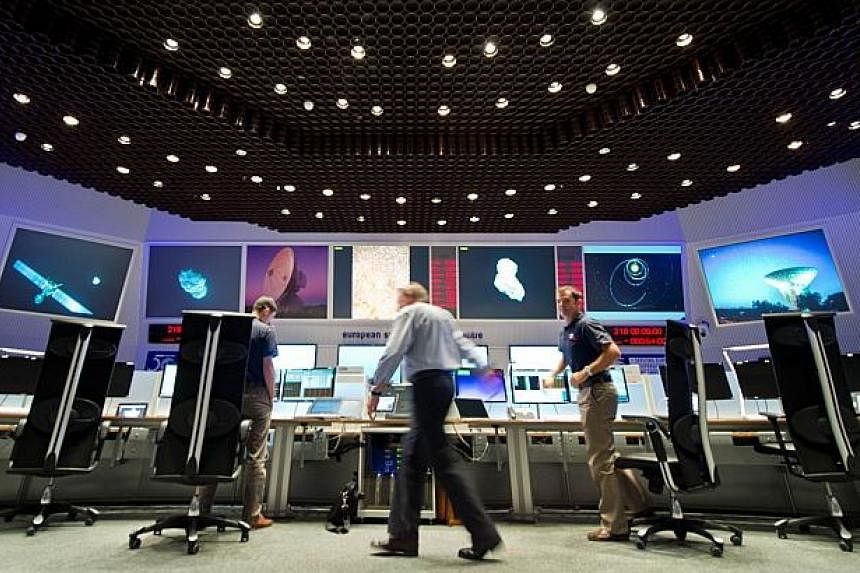 Scientists follow the flight of the Rosetta spacecraft from the control centre of the European Space Agency (ESA) in Darmstadt, western Germany on Aug 6, 2014. -- PHOTO: AFP