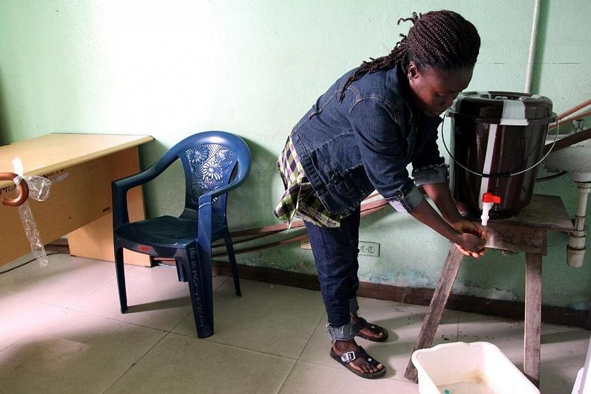 A woman washes her hands with chlorine water to prevent contracting Ebola at a public health centre on July 31, 2014, in Monrovia. -- PHOTO: AFP