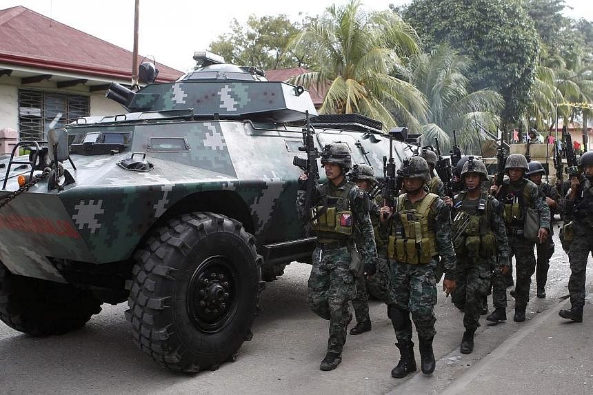 Members of the elite Special Action Police walk next to an armoured vehicle as they reinforce soldiers battling Muslim rebels from the Moro National Liberation Front (MNLF) in Zamboanga city, in southern Philippines in this Sept 12, 2013, file photo.