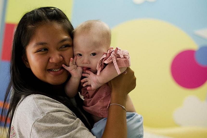 Thai surrogate mother Pattaramon Chanbua (left) holds her baby Gammy, born with Down Syndrome, at the Samitivej hospital, Sriracha district in Chonburi province on Aug 4, 2014. -- PHOTO: AFP