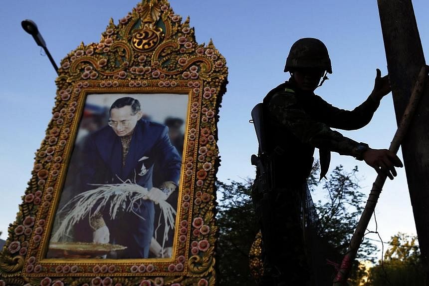 A soldier climbs a barricade in front of a picture of Thailand's King Bhumibol Adulyadej as his unit dismantles an anti-government encampment in central Bangkok on May 23, 2014. -- PHOTO: REUTERS