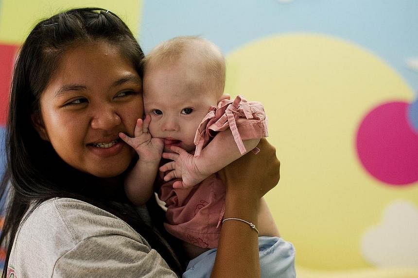 Thai surrogate mother Pattaramon Chanbua holds her baby Gammy, born with Down syndrome, at the Samitivej hospital, Sriracha district in Chonburi province on Aug 4, 2014. -- PHOTO: AFP