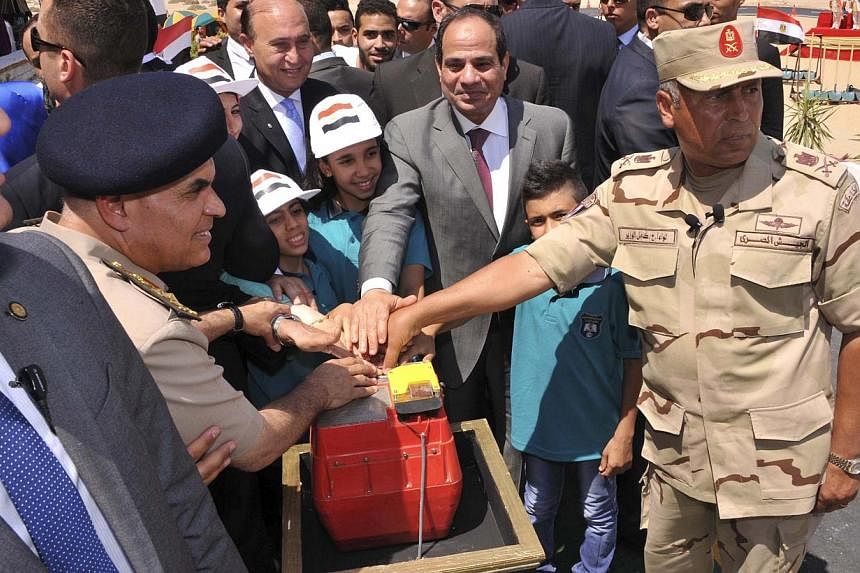 Egyptian President Abdel Fattah al-Sisi&nbsp;(centre), military personnel and children place their hands on a detonator at an event marking the announcement of plans for a major upgrade of the Suez Canal, in Cairo August 5, 2014. Egypt said on Tuesda