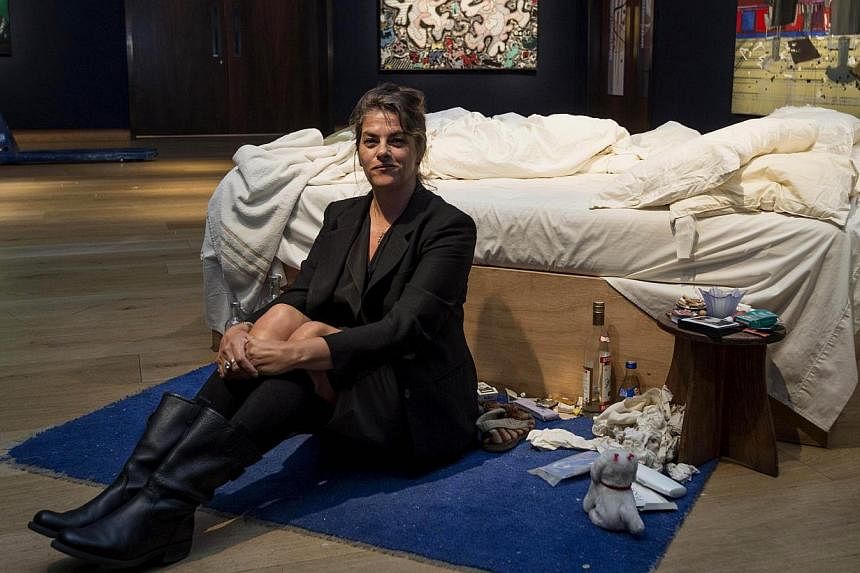In this file picture taken on June 27, 2014, British artist Tracey Emin sits on her iconic art installation, "My Bed" during a press preview at Christie's auction house. Tracey Emin's unmade bed artfully littered with condoms, cigarette packs and und