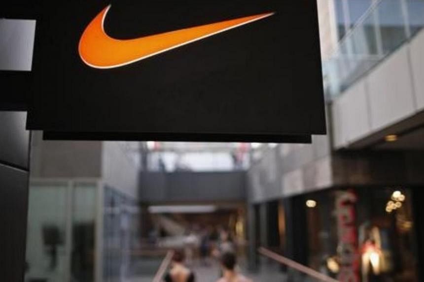 People walk past a Nike shop under the company logo at the Sanlitun shopping area in central Beijing. -- PHOTO: REUTERS&nbsp;