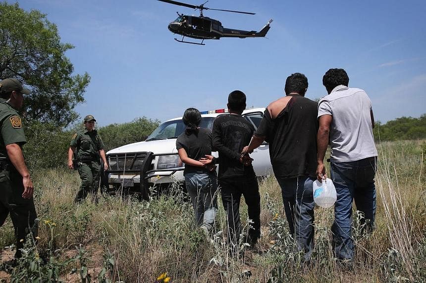 US Customs and Border Protection agents take undocumented immigrants into custody on July 22, 2014 near Falfurrias, Texas.&nbsp;As President Barack Obama considers sidestepping Congress to loosen US immigration policy, a Reuters/Ipsos poll shows Amer