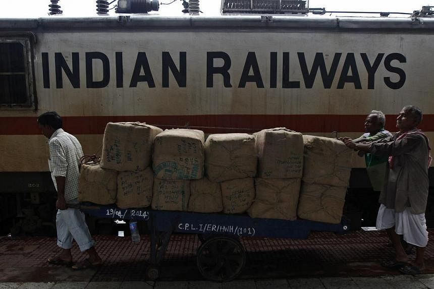 Porters transport goods on a hand-pulled trolley to load onto a train at a railway station in Kolkata on July 8, 2014. -- PHOTO: REUTERS