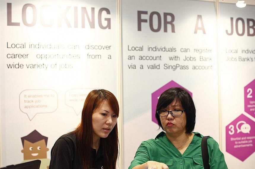 Singapore Workforce Development Agency career coach, Goh Xiao Shi, 28 (left) helps a job applicant look through a jobs registry offered on Jobs Bank's website on July 14, 2014. The national Jobs Bank has accumulated more than 52,000 job vacancies, le