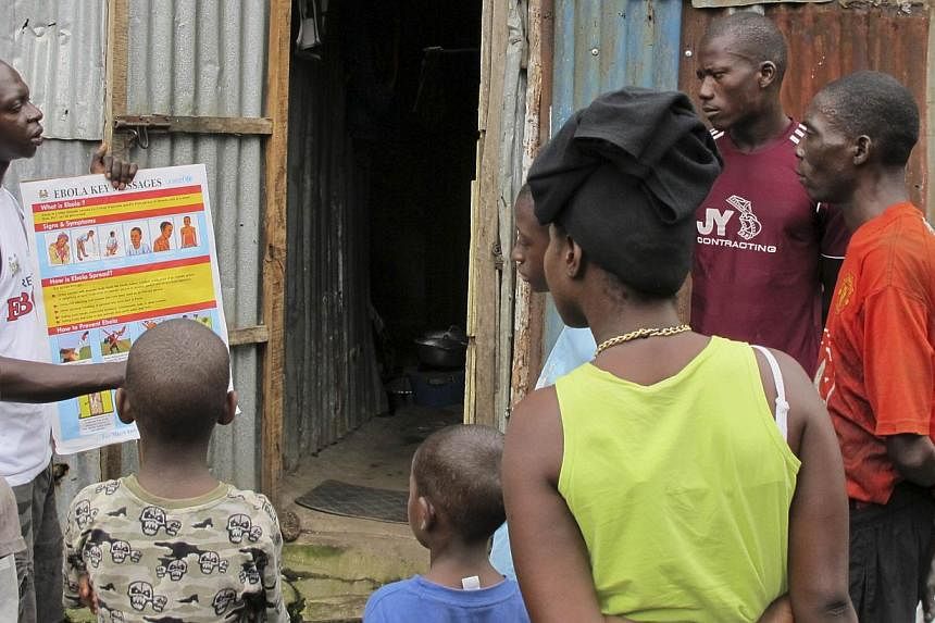 An outreach worker speaks with residents about the information on the symptoms of Ebola virus disease (EVD) and best practices to help prevent its spread, in Freetown, Sierra Leone in this Aug, 2014 handout photo provided by UNICEF Aug 6, 2014. -- PH