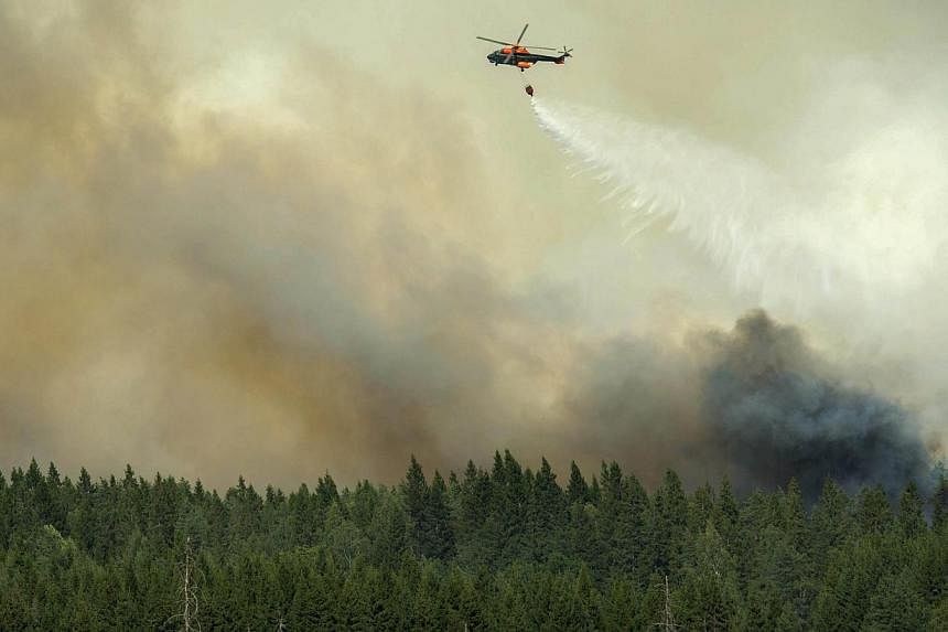 A helicopter drops its load of water on the wildfire front just outside the evacuated village of Gammelby near Sala, in central Sweden, on August 4, 2014. The fire, which has destroyed 100 sq km of forest,&nbsp;is&nbsp;the worst seen in Scandinavia i