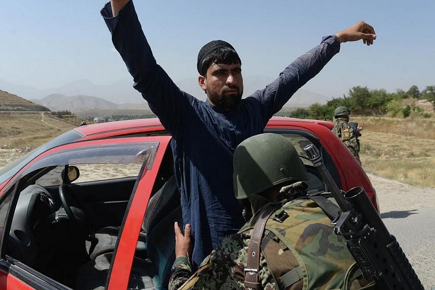 An Afghan National Army soldier searches passengers at a checkpoint near the Marshal Fahim National Defence University, a training complex on the outskirts of Kabul on August 6, 2014 where an&nbsp;Afghan opened fire on a high-ranking delegation on Tu