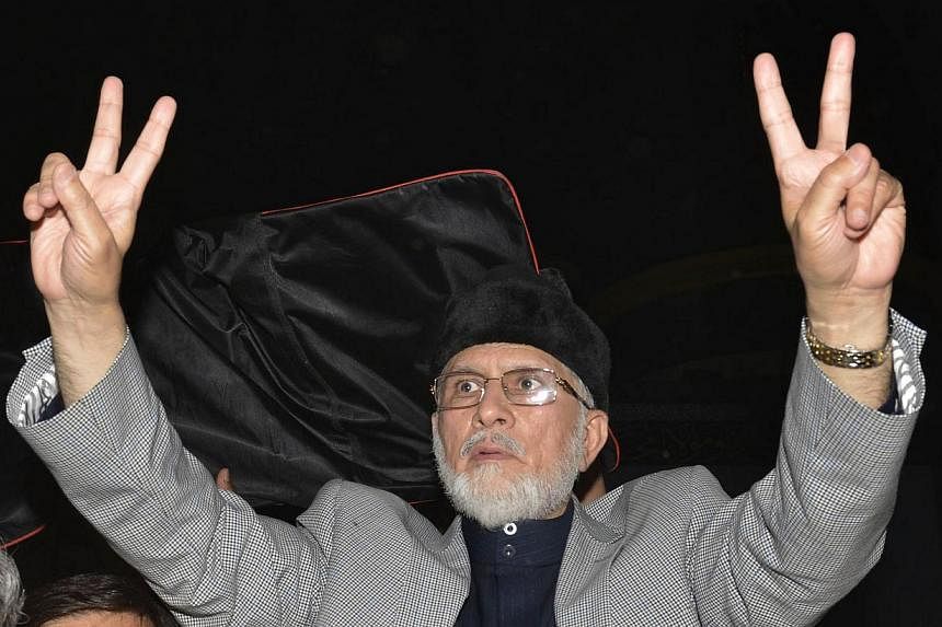 Pakistani cleric Tahir-ul-Qadri flashes a 'victory sign' as he addresses supporters at a rally in Lahore on June 23, 2014.&nbsp;Tahir-ul-Qadri&nbsp;threatened on Thursday, Aug 7 to march on the Pakistani capital and overthrow the government of Prime 
