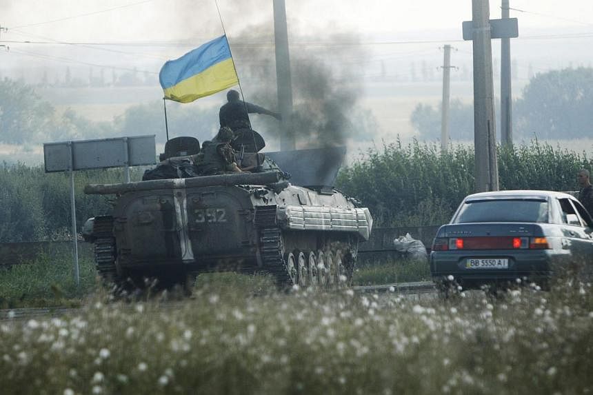 Ukrainian servicemen drive a military armoured vehicle along a road in Donetsk region on August 6, 2014. -- PHOTO: REUTERS
