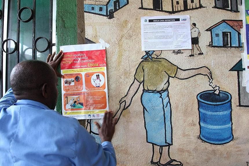 A nurse sets an information sign about Ebola on a wall of a public health centre on July 31, 2014, in Monrovia. -- PHOTO: AFP