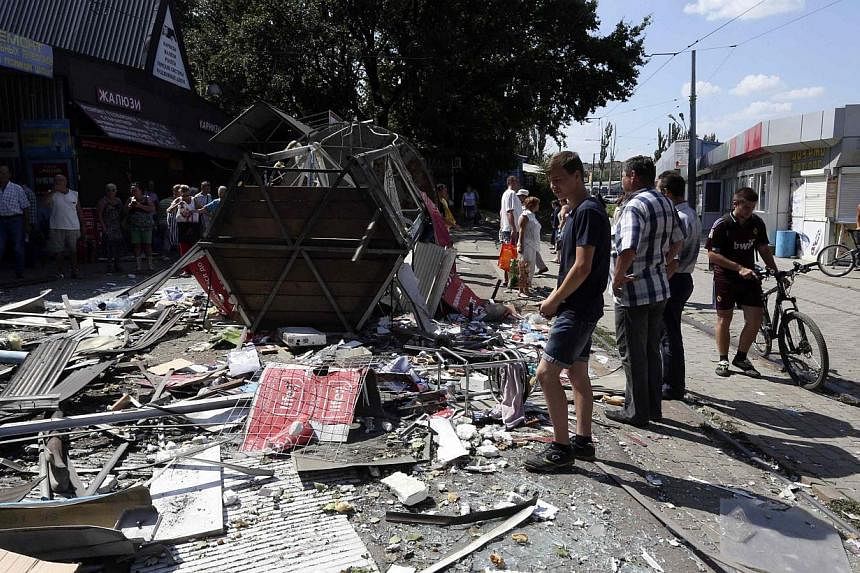 People gather near a damaged building following what locals say was a recent airstrike by Ukrainian forces in Donetsk on August 6, 2014. -- PHOTO: REUTERS