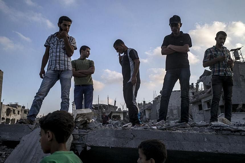 Palestinians stand on top of a destroyed building in the devastated neighbourhood of Shejaiya in Gaza City on Aug 6, 2014. Two senior Hamas officials said the Palestinian militant movement will not extend a 72-hour ceasefire, accusing Israel of rejec