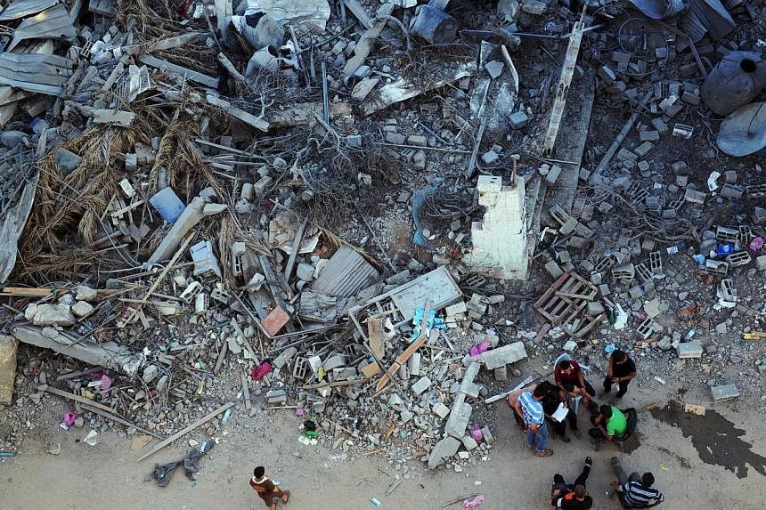 Residents gather next to the rubble of a destroyed building in the devastated neighbourhood of Shejaiya in Gaza City on Aug 7, 2014. -- PHOTO: AFP