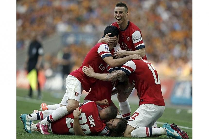 Arsenal players celebrate with Welsh midfielder Aaron Ramsey (ground-obscured) after he scored the third and winning goal during the English FA Cup final match between Arsenal and Hull City at Wembly Stadium in London on May 17, 2014.&nbsp;Arsenal fa