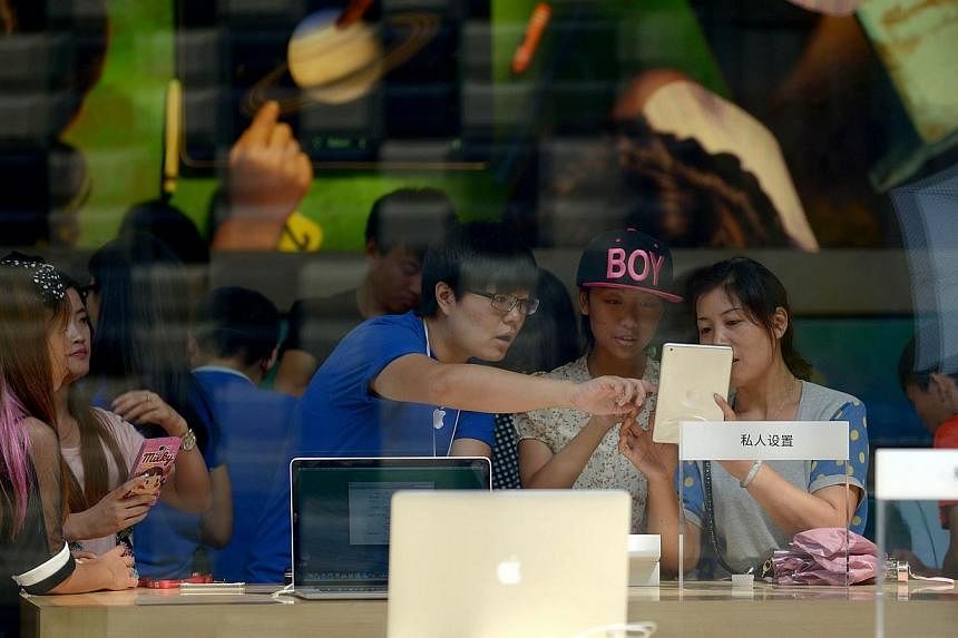 A salesman introduces products to customers at an Apple store in Beijing on Aug 8, 2014.&nbsp;Apple products such as laptops and tablets are not banned from Chinese government procurement lists, according to the country's chief procurement centre, re