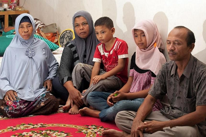 Missing Indonesian tsunami victim Raudhatul Jannah (second right), aged 14, sits with mother Jamaliah (second left), holding youngest son Jumadi Rangkuti (centre) and father Septi Rangkuti (extreme right), joined by Syarwani (left), the foster mother