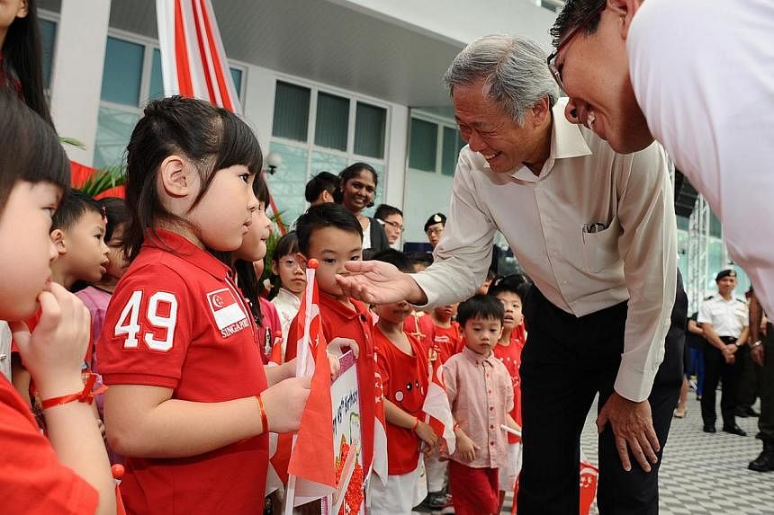 Minister for Defence Dr Ng Eng Hen (second right) and Minister of State for Defence Dr Mohamad Maliki Bin Osman interacting with children from Cherie Hearts @ Gombak after a ceremony celebrating Singapore's 49th birthday on Aug 8, 2014. -- PHOTO: MIN