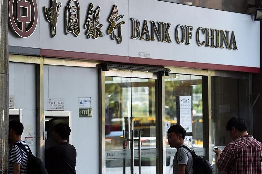 People waiting outside a Bank of China branch in Beijing on July 11, 2014.&nbsp;Bankers from major listed lenders such as Bank of China say they are further cutting lending to riskier borrowers, in particular smaller private companies. -- PHOTO: AFP