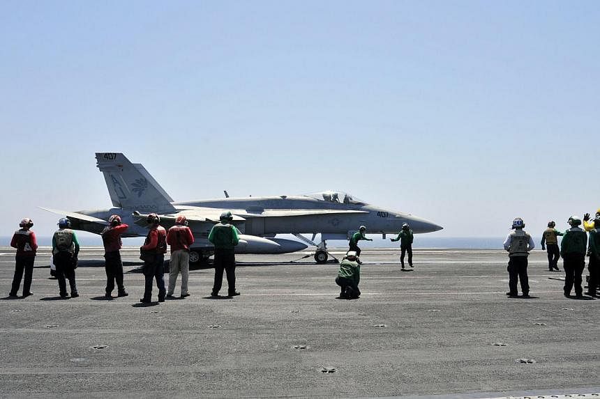 Sailors make final inspections on an F/A-18C Hornet assigned to the Golden Warriors of Strike Fighter Squadron (VFA) 87 aboard the aircraft carrier USS George H.W. Bush (CVN 77) in the Gulf, on Aug 7, 2014. -- PHOTO: REUTERS