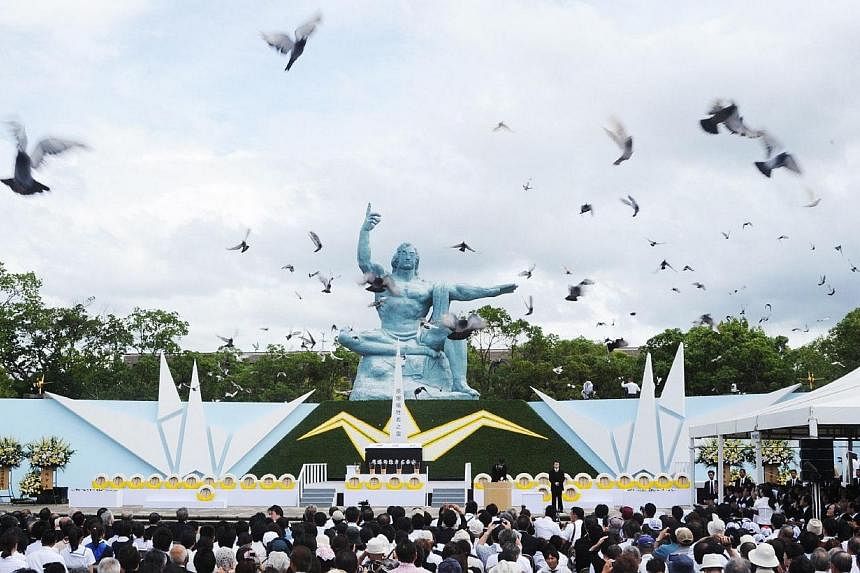Pigeons fly around the peace statue during a memorial service for victims of the 1945 atomic bombing, at Nagasaki Peace Park on Aug 9, 2014.&nbsp;Tens of thousands marked the 69th anniversary of the US atomic bombing of Nagasaki on Saturday, Aug 9, 2