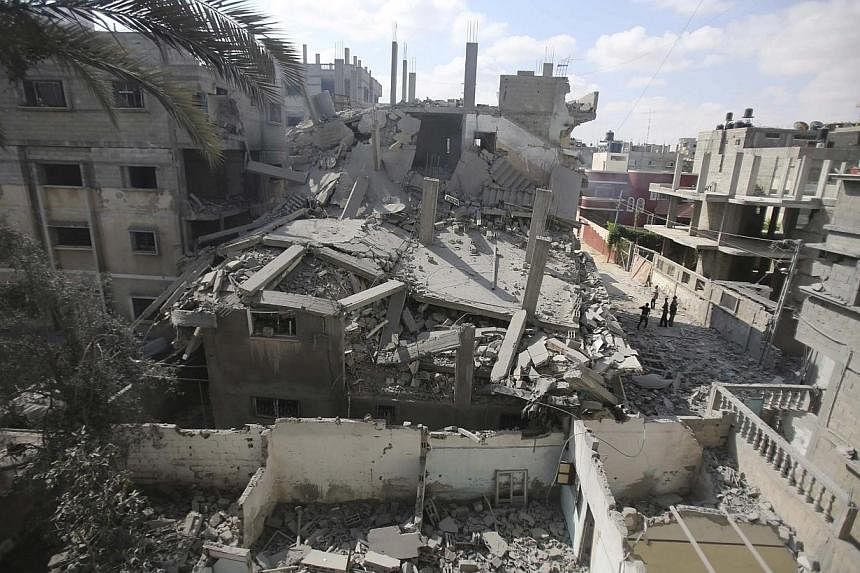 Palestinians look at the remains of a house, which witnesses said was hit by an Israeli air strike in Rafah in the southern Gaza Strip on Aug 9, 2014.&nbsp;Israeli warplanes kept up a punishing campaign of air strikes over Gaza, killing five Palestin