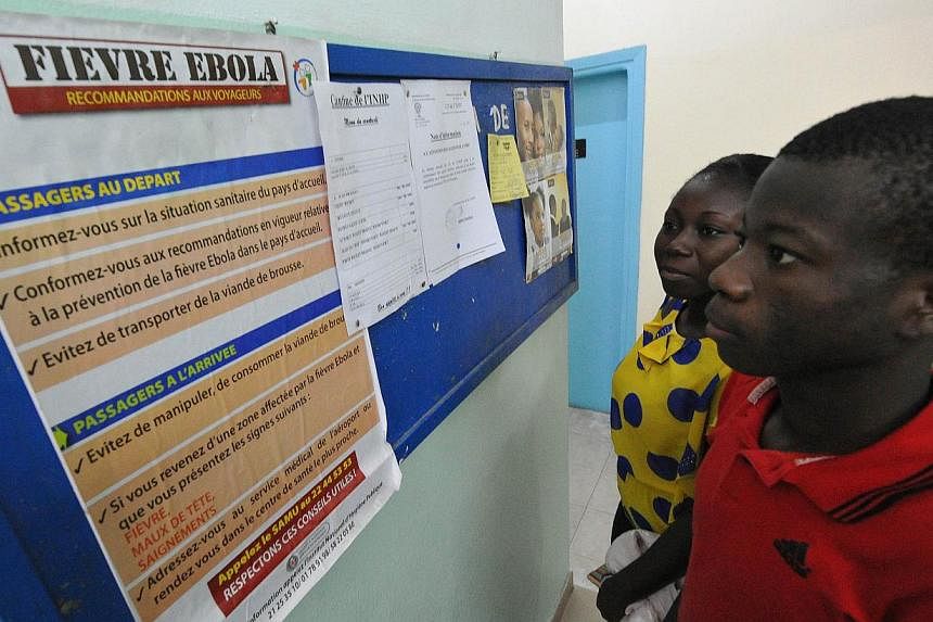 People read a poster bearing informations for travellers arriving in or departing from areas affected by the Ebola virus, on Aug 8, 2014 at the national public health institute in Abidjan. -- PHOTO: AFP