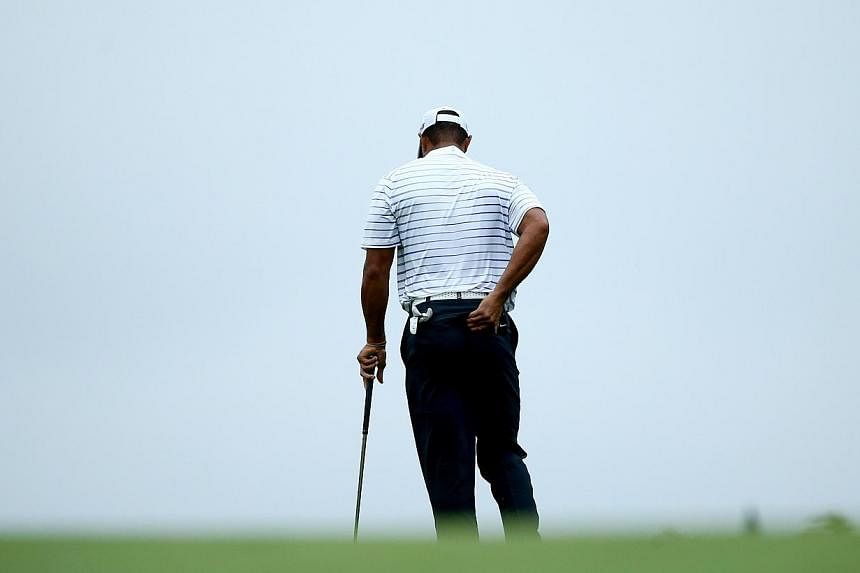 Tiger Woods of the United States rubs his back before hitting his second shot on the 17th hole during the second round of the 96th PGA Championship at Valhalla Golf Club on Aug 8, 2014, in Louisville, Kentucky.&nbsp;-- PHOTO: AFP&nbsp;