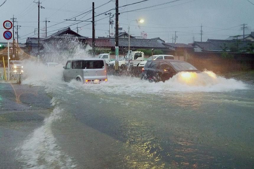 Vehicles drive down a flooded road in the city of Tsu, Mie prefecture as Typhoon Halong brings rain -- PHOTO: AFP