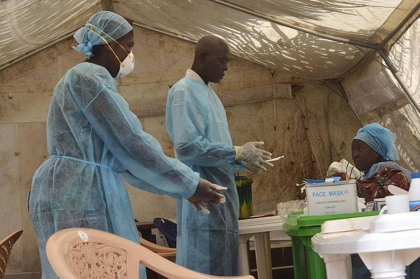 Health workers take blood samples for Ebola virus testing at a screening tent in the local government hospital in Kenema, Sierra Leone, on June 30, 2014. - PHOTO: REUTERS