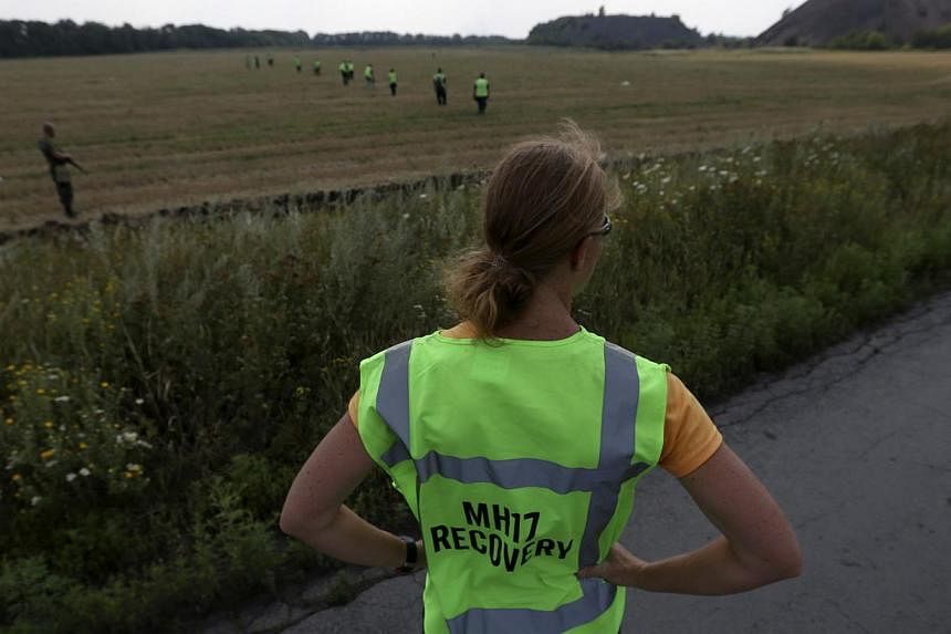 A forensic expert watches as recovery work continues at the site of the downed Malaysian airliner MH17 near the village of Rozsypne in the Donetsk region August 4, 2014. Dutch forensic experts have identified a total of 65 victims as of Saturday, as 