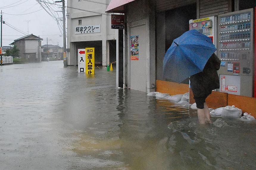 A local resident walks in a flooded street caused by Typhoon Halong's passing in Tokushima on Aug 10, 2014.&nbsp;-- PHOTO: AFP