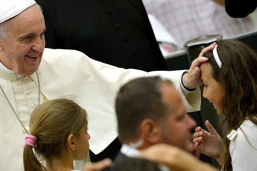 Pope Francis blesses a girl as he arrives for his weekly audience in the Paul VI hall in the Vatican on Aug 6, 2014. -- PHOTO: AFP&nbsp;