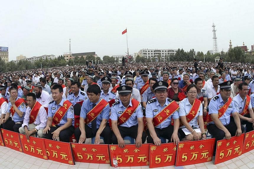 Police wearing sashes hold placards during a ceremony to award those who the authorities say participated in "the crackdown of violence and terrorists activities" in Hotan, Xinjiang Uighur Autonomous Region on Aug 3, 2014.&nbsp;Chinese authorities sa