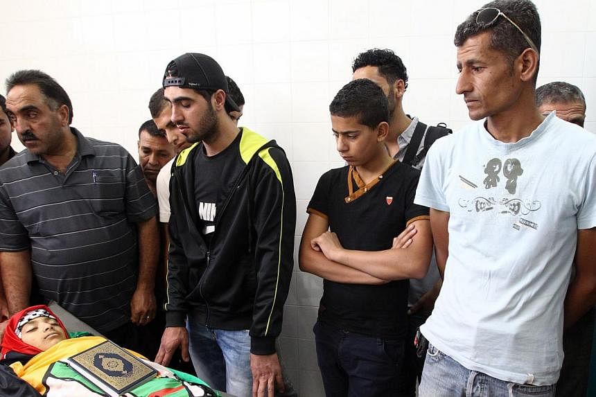 Relatives mourn over the body of Mohammed Khalil al-Anati, a 11-year-old Palestinian who was reportedly shot dead by Israeli soldiers in al-Fawwar refugee camp on Aug 10, 2014, at al-Ahli hospital in the city of Hebron in the southern West Bank.&nbsp