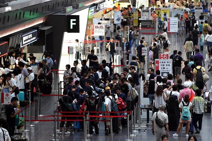 Passengers line up to check in for their flights at the Haneda airport terminal in Tokyo on Aug 10, 2014. -- PHOTO: AFP