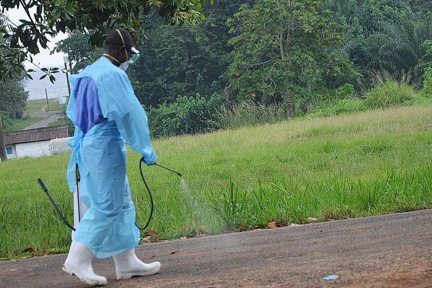 A file photo taken on July 24, 2014 shows a staff member of the Christian charity Samaritan's Purse spraying product as he treats the premises outside the ELWA hospital in the Liberian capital Monrovia. Guinea announced on August 9, 2014 it was closi