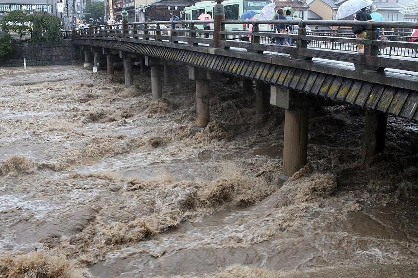 This picture taken on August 10, 2014 shows muddy water running under a wooden made bridge in Kyoto, western Japan. -- PHOTO: AFP