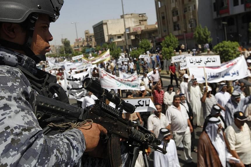 An Iraqi police officer stands guard during a demonstration in support of Iraqi Prime Minister Nuri al-Maliki in Baghdad, on Aug 9, 2014. -- PHOTO: REUTERS